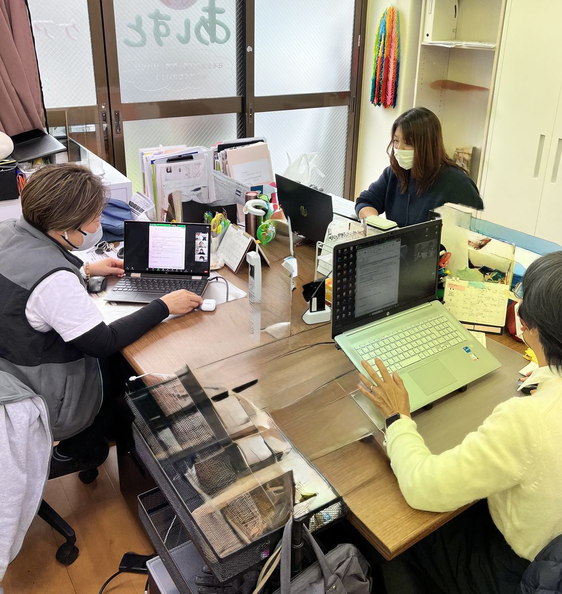 事務所でパソコンを前に打ち合わせをするケアマネジャーたち