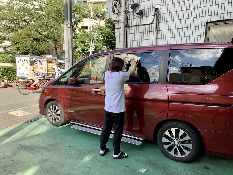 送迎車のドアを開けて利用者を迎えるスタッフ