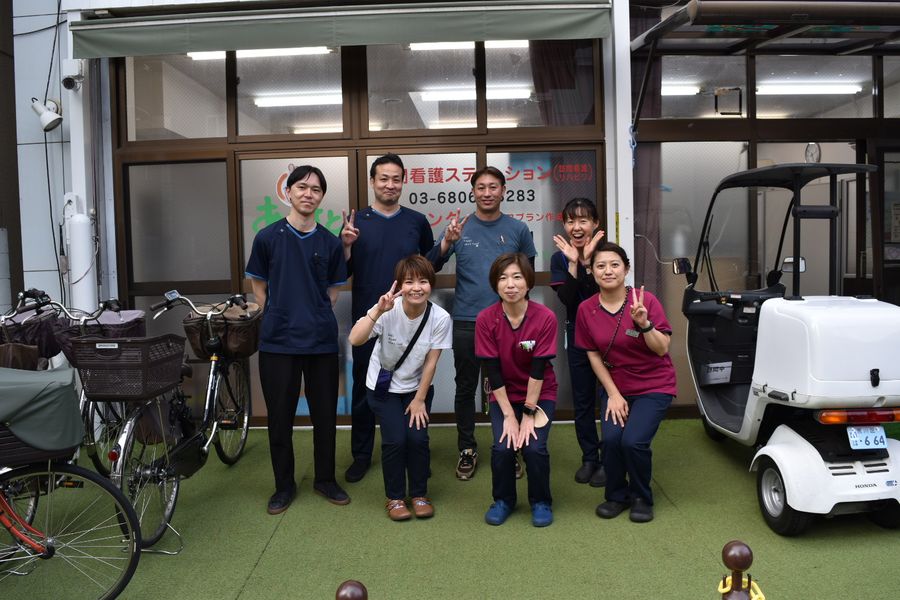 事業所の前に並ぶスタッフと小型の電動車両