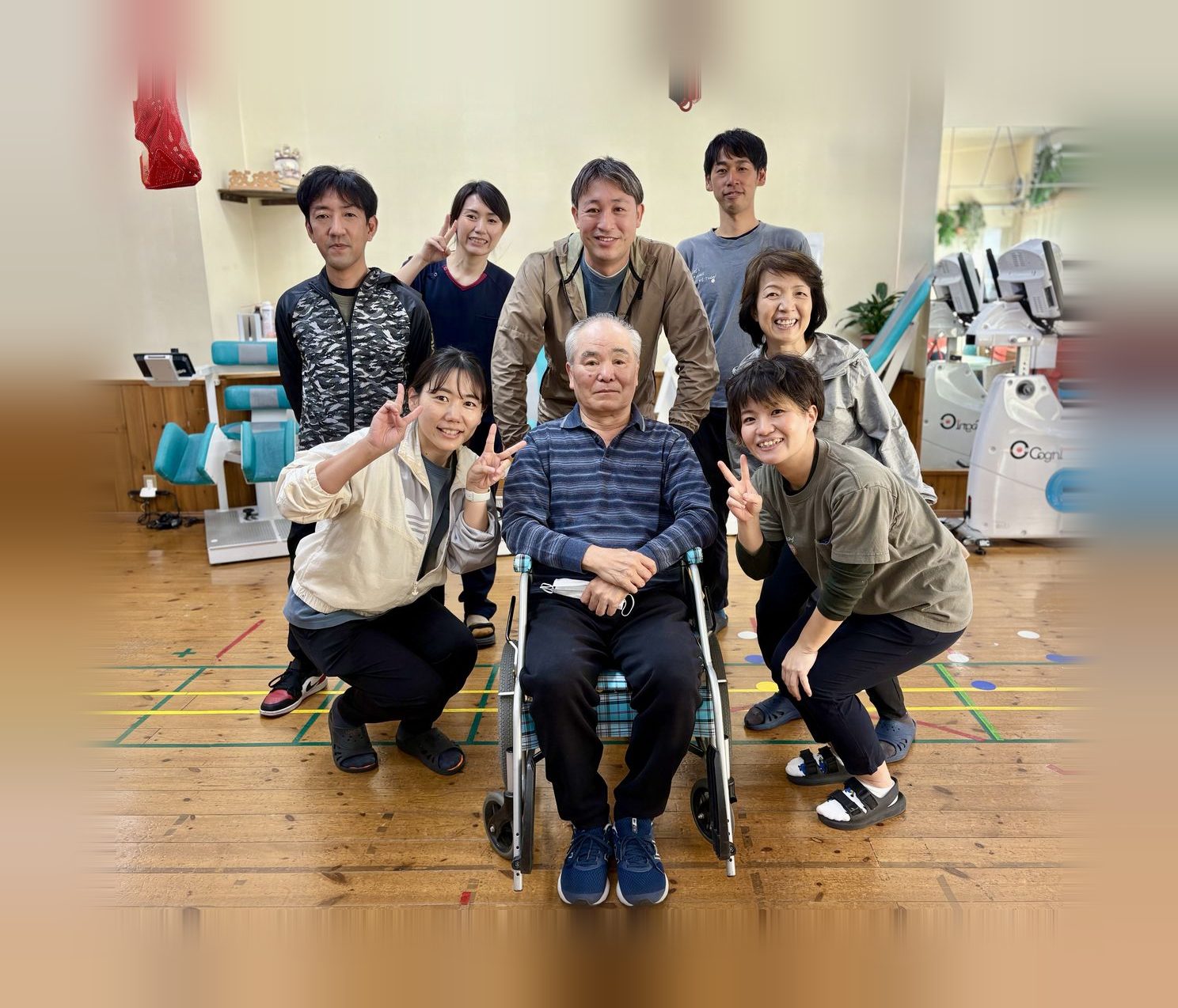 車いすの利用者を囲んで笑顔でポーズをとるスタッフたち