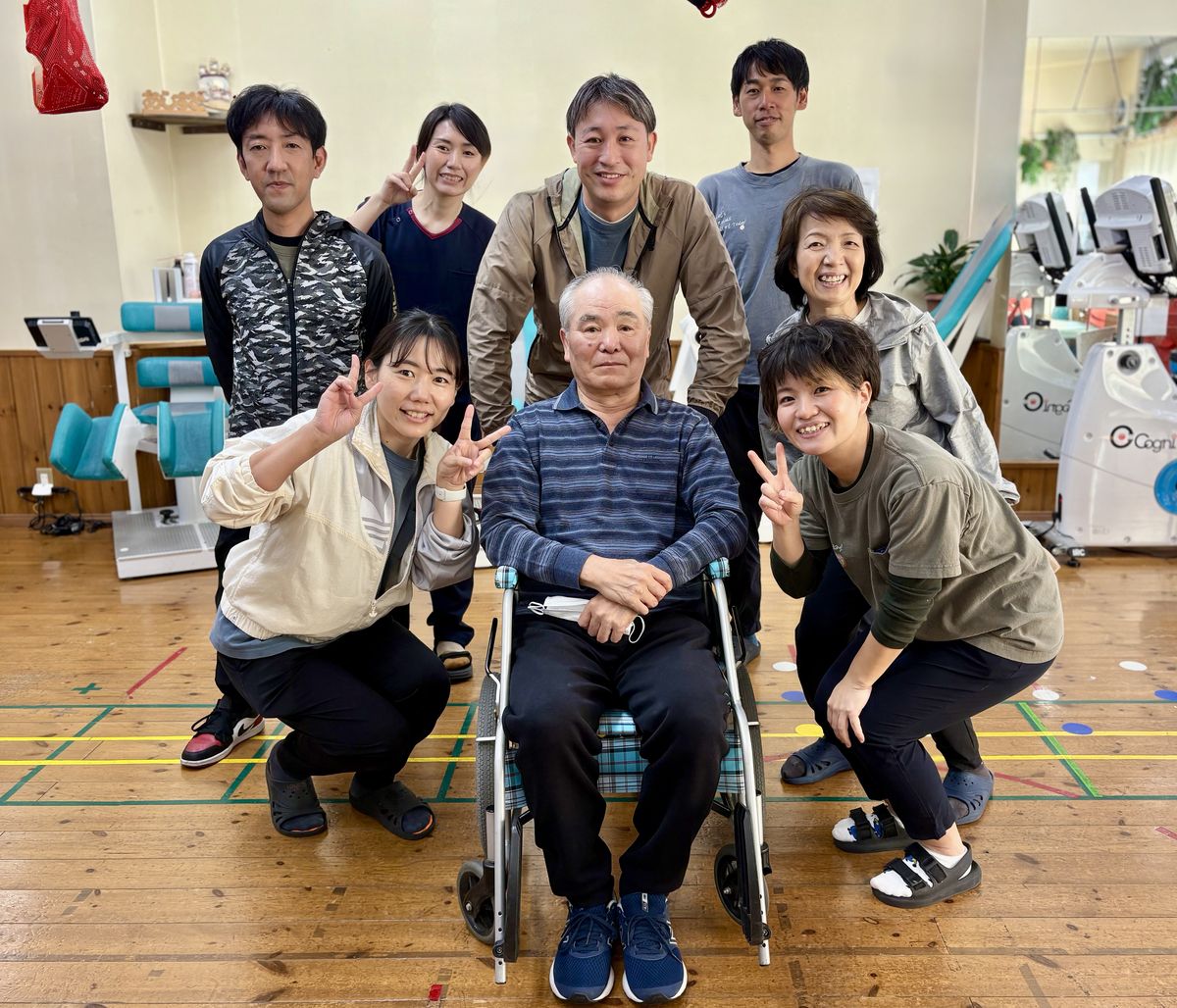 車いすの利用者を囲んで笑顔でポーズをとるスタッフたち